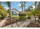 A walkway leads to a charming home, showcasing a light blue deck, lush landscaping, and mature palm trees at 515 Frank Lloyd Wright Way, Lakeland, FL 33803