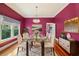 Elegant dining room with a glass table, vibrant walls, and modern chandelier at 515 Frank Lloyd Wright Way, Lakeland, FL 33803