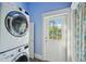 A compact laundry featuring a stacked washer and dryer, with natural light coming in from the door at 515 Frank Lloyd Wright Way, Lakeland, FL 33803