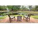 Inviting backyard view with wooden deck, fire pit, chairs, and picturesque pond with fountain feature at 472 Blue Heron Cir, River Ranch, FL 33867