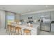 Bright kitchen featuring stainless steel appliances, a large island with seating, and stylish grey cabinets at 2418 Slippery Rock St, Auburndale, FL 33823