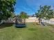 Large backyard featuring green grass, a playset with slide, trampoline, and a white vinyl perimeter fence at 6272 Cornerstone Dr, Lakeland, FL 33813