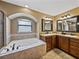 Spacious bathroom features a soaking tub, a window with natural light, and wood cabinets at 6272 Cornerstone Dr, Lakeland, FL 33813