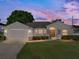Charming home featuring manicured lawn, stone accents, and an attached two-car garage at twilight at 6272 Cornerstone Dr, Lakeland, FL 33813