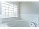 Close-up of a soaking tub with a glass block window providing natural light at 3518 Remington Oaks Way, Lakeland, FL 33810