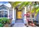 Welcoming front entrance with a bright yellow door, decorative columns, and colorful tropical plants at 3518 Remington Oaks Way, Lakeland, FL 33810