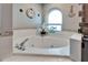 Bathroom featuring a large corner tub with tile surround and a window with nautical decor at 7402 Gunstock Dr, Lakeland, FL 33809
