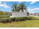 Community entrance sign with landscaping, two palm trees, and blue skies at 356 Loch Ct, Davenport, FL 33837