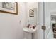 Bright powder room featuring a pedestal sink, decorative mirror and light fixture at 356 Loch Ct, Davenport, FL 33837