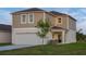 Two-story home features a two-car garage, covered porch, and manicured lawn at 2004 Marigold Aly, Winter Haven, FL 33884