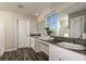 Bright bathroom with a double sink vanity, dark wood floor, framed mirror, and a window at 2212 Canyon Oak Dr, Davenport, FL 33837