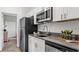 Modern kitchen with stainless steel appliances, white cabinets, and a gray countertop with stylish decor at 3317 Armstrong Ave, Clermont, FL 34714