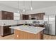 A modern kitchen featuring brown cabinets, stainless steel appliances, and an island with a white countertop at 438 Cotswold Cir, Davenport, FL 33837