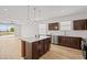 Bright, modern kitchen with brown cabinets, a wooden island, stainless steel appliances, and light wood floors at 438 Cotswold Cir, Davenport, FL 33837