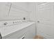 Bright laundry room featuring a white washer and dryer with wire rack shelving and door at 438 Cotswold Cir, Davenport, FL 33837