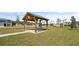 Community park with a wooden pergola, large green lawn, and a playground with a slide in the background at 1366 Blue Ash Ln, Deland, FL 32720