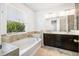 Bright bathroom featuring a soaking tub, dual sinks, and large window at 2846 Sera Bella Way, Kissimmee, FL 34744