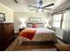 Well-lit bedroom features a ceiling fan, wood dresser, and coordinating lamps and decor at 1464 Mount Pleasant Rd, Groveland, FL 34736