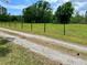 Gravel drive on a vast, grassy property marked by wooden fences, creating a rustic, pastoral scene at 1464 Mount Pleasant Rd, Groveland, FL 34736