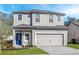 Charming two-story home featuring a well-manicured lawn, gray siding, and a vibrant blue front door at 13280 Tula Loop, Astatula, FL 34705