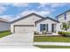 Charming single-story home with a two-car garage, blue accents, and well-manicured landscaping at 1794 White Elephant Loop, Winter Haven, FL 33884