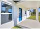 Covered entryway with a bright blue door, a small window, and a view of the surrounding landscape at 12921 Sw 64Th Terr Rd, Ocala, FL 34473