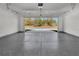 Spacious garage with epoxy floor overlooking a road surrounded by luscious trees at 12921 Sw 64Th Terr Rd, Ocala, FL 34473