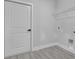 Bright laundry room features gray wood-look flooring, utility connections and a wire storage shelf at 12921 Sw 64Th Terr Rd, Ocala, FL 34473