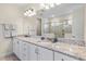 Bathroom with double sink vanity, granite countertops, and shower behind glass doors at 321 Auburn Ave, Kissimmee, FL 34747