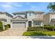 Charming two-story home featuring a brick driveway, a two-car garage, and manicured landscaping at 321 Auburn Ave, Kissimmee, FL 34747