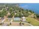 Aerial view showcasing a neighborhood with mature trees, lakeside access, and a community tennis court at 5144 Riverlake Dr, Bartow, FL 33830