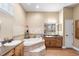 Bright bathroom featuring tile floors, wood cabinets, granite countertops, and a large soaking tub at 5144 Riverlake Dr, Bartow, FL 33830