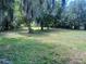 Backyard featuring a grassy lawn with shady trees in the background at 5580 Hwy 542 W, Winter Haven, FL 33880