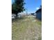 A grassy front yard is partially bordered by a wooden fence with a commercial building shown in the background at 5580 Hwy 542 W, Winter Haven, FL 33880
