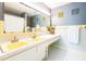 Bathroom with double sinks, a large mirror, yellow accents, and white and blue patterned floors at 2908 Maplewood Ave, Lakeland, FL 33803