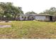 Single story home with a gray brick exterior, lawn, mature trees and blue sky at 2908 Maplewood Ave, Lakeland, FL 33803
