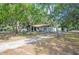 Welcoming single-story home with brick and covered entry, mature trees and a spacious gravel driveway at 3365 Bahama Ct, Lake Wales, FL 33898