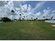 Large green area with space for lawn games with palm trees and homes under a partly cloudy sky at 65 Joppa Dr, Winter Haven, FL 33884