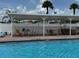 Outdoor patio area with poolside seating, featuring patio tables and chairs, and a bright white canopy at 65 Joppa Dr, Winter Haven, FL 33884