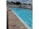 Clear swimming pool with pristine blue water, surrounded by a red brick tiled deck and white vinyl fencing at 65 Joppa Dr, Winter Haven, FL 33884