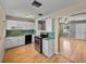 Kitchen featuring white cabinets, laminate floors, a black stove, and a view into the living room at 3928 Cherry Way, Lakeland, FL 33805