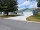 Inviting single-story home with a pristine white driveway, lush lawn, and vibrant blue siding at 1219 Santos Pl, Lady Lake, FL 32159