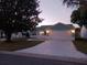 Charming single-story home with a well-manicured lawn and patterned concrete driveway at twilight at 1219 Santos Pl, Lady Lake, FL 32159