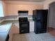 Efficient kitchen with light wood cabinets, black appliances, and neutral tile flooring at 1219 Santos Pl, Lady Lake, FL 32159