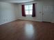 Bright living room with laminate floors, a window with red curtains, and a white interior door at 1219 Santos Pl, Lady Lake, FL 32159