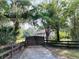 View of the gated driveway leading to the two-story home with a red roof surrounded by lush trees at 18700 Ravenswood Rd, Altoona, FL 32702