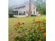 Charming two-story home featuring a screened porch, brick chimney, and blossoming orange flowers at 18700 Ravenswood Rd, Altoona, FL 32702