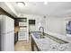 Well-lit kitchen features granite countertops, dark cabinets, stainless steel sink, and a white refrigerator and stove at 490 N Pin Oak Pl # 112, Longwood, FL 32779