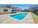 Stunning backyard with a sparkling pool, travertine deck, and lush landscaping, perfect for relaxation at 12329 Sw 140Th Loop, Dunnellon, FL 34432