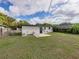 The backyard has a small concrete patio with a gray home, grass, a fence and trees at 2625 Williston Dr, Lakeland, FL 33801